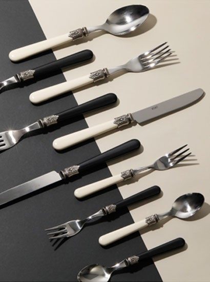 Cutlery set with ivory and black handles and decorative metal collars